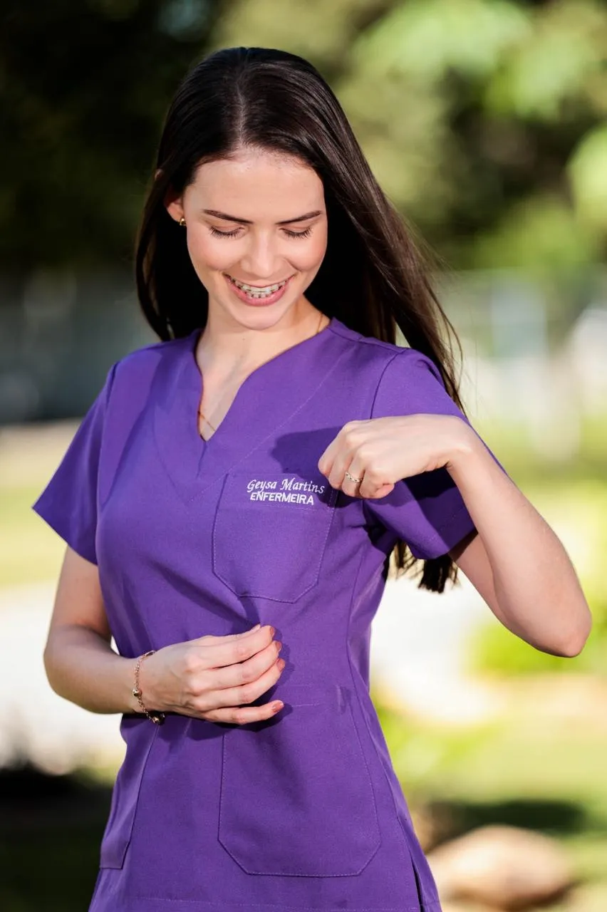 Profissional de saúde vestindo scrub roxo com o nome bordado no peito
